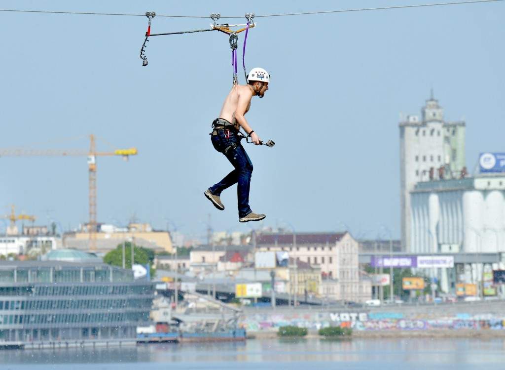 A man, hung by his back skin, crosses the Dniper river on a 552-meter long cable between the two banks of the river in Kiev. (AFP PHOTO/ SERGEI SUPINSKY)