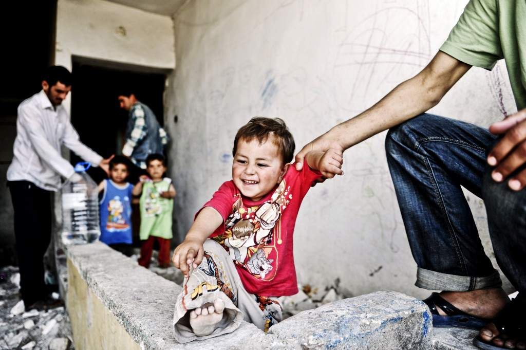 A Syrian man holds his infant in front of a disused house in the Fikirtepe area of Istanbul. (AFP PHOTO / OZAN KOSE)