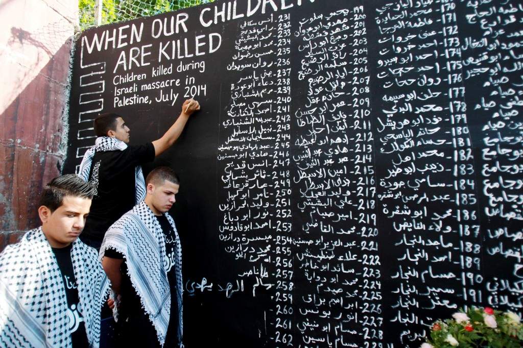 Palestinian youths list the names of the children who were killed in the ongoing Israeli devastating military assault on the Gaza Strip. (AFP PHOTO/ MUSA AL SHAER)