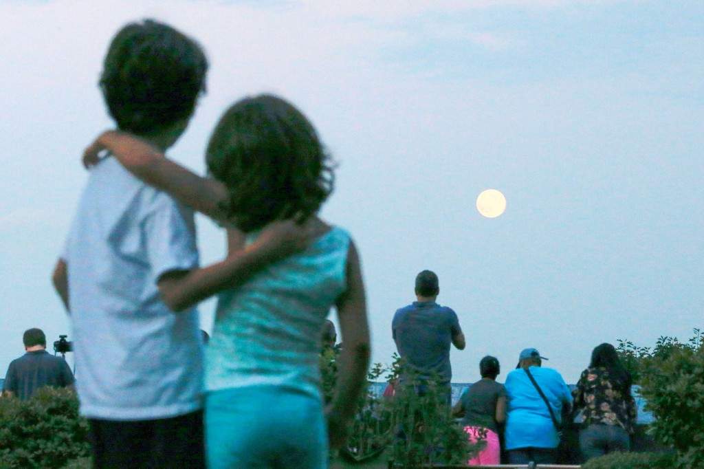 Children watch a full moon known as a 'supermoon' while it rises over the skyline of New York and the Empire State Building, as seen from the Eagle Rock Reservation in West Orange, New Jersey. (REUTERS/Eduardo Munoz)