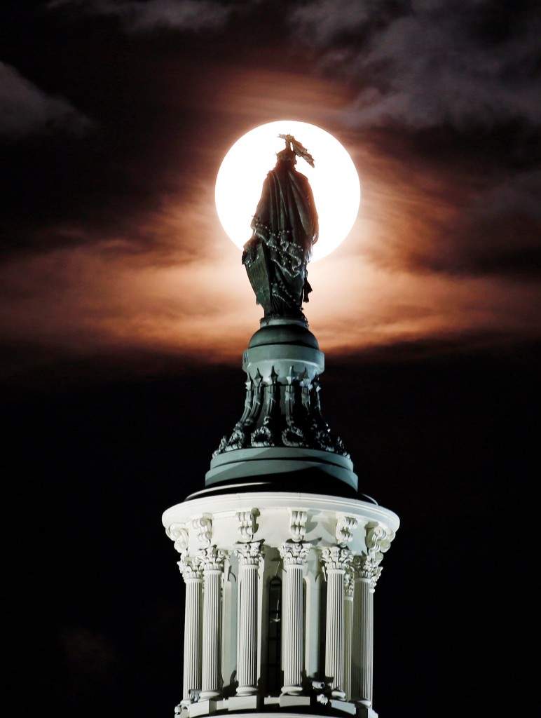The supermoon is seen as it rises through the clouds behind the bronze Statue of Freedom by Thomas Crawford atop the US Capitol. (AP Photo/Alex Brandon)