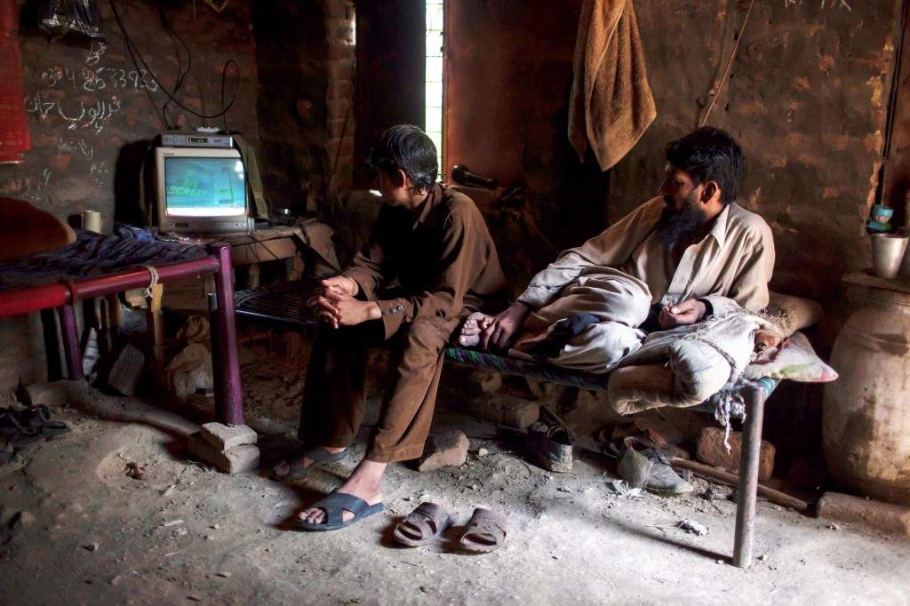 Miners watch TV in a room at a coal field in Choa Saidan Shah