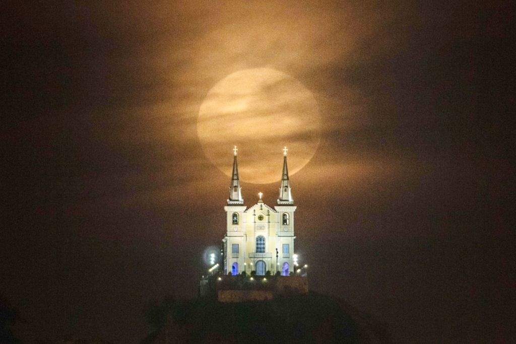 The full moon descends behind the Nossa Senhora da Penha Church in Rio de Janeiro. (AFP PHOTO / YASUYOSHI CHIBA)