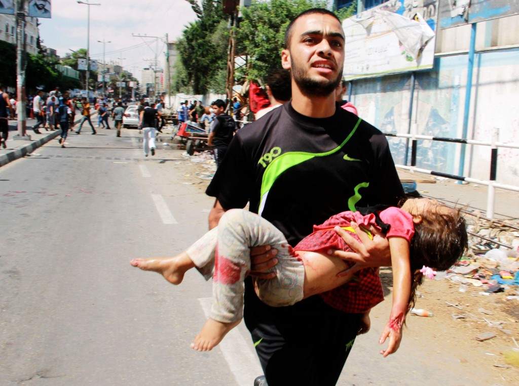 A Palestinian man carries a child killed in a blast outside a UN run school in Rafah, in the southern Gaza Strip. (AP Photo/Hatem Ali)