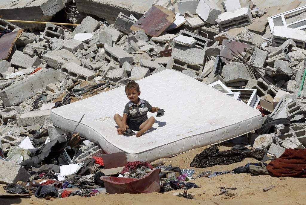 A Palestinian child sits on a mattress on the rubble of a house which was destroyed in an Israeli air strike on Abasan, east of the southern Gaza Strip town of Khan Yunis and close to the border with Israel. (AFP PHOTO/SAID KHATIB)