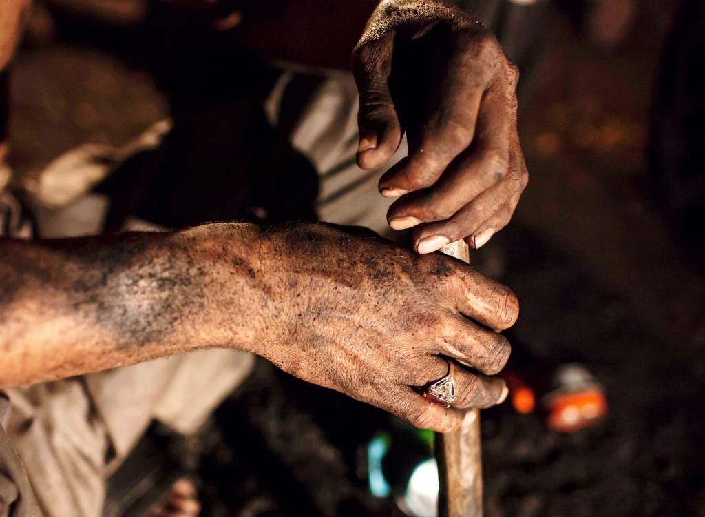 A miner covered in coal dust sits inside a mine in Choa Saidan Shah, Punjab province