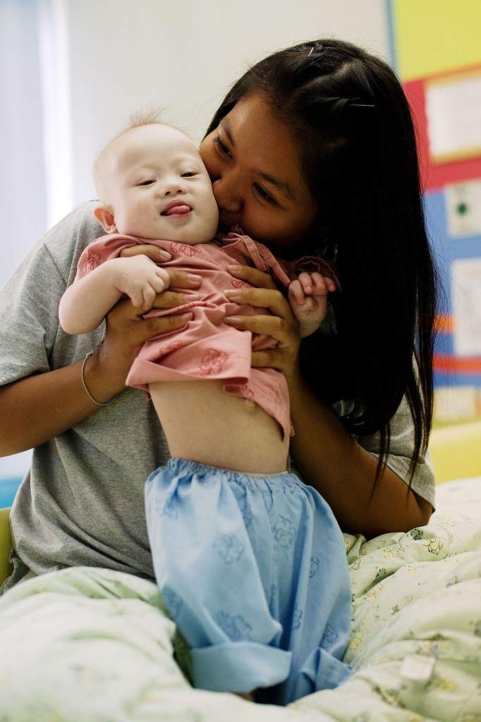 Thai surrogate mother Pattaramon Chanbua (back) plays with her baby Gammy, born with Down Syndrome, at the Samitivej hospital, Sriracha district in Chonburi province. (AFP PHOTO / Nicolas ASFOURI)