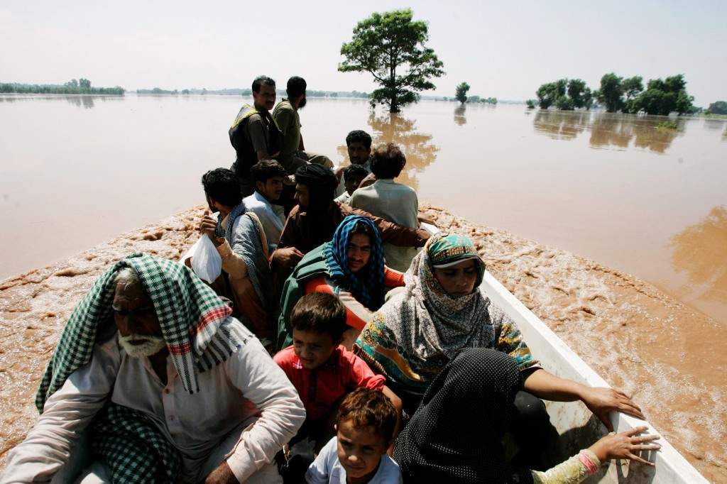 Flood victims sit in a boat after being rescued by soldiers of the Pakistan Army, after heavy rain in Wazirabad, located in Gujranwala
