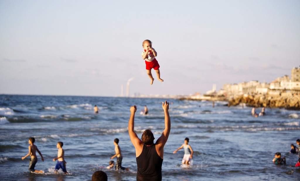 A Palestinian man plays with his baby on a beach in Gaza city. (AFP PHOTO/MAHMUD HAMS)