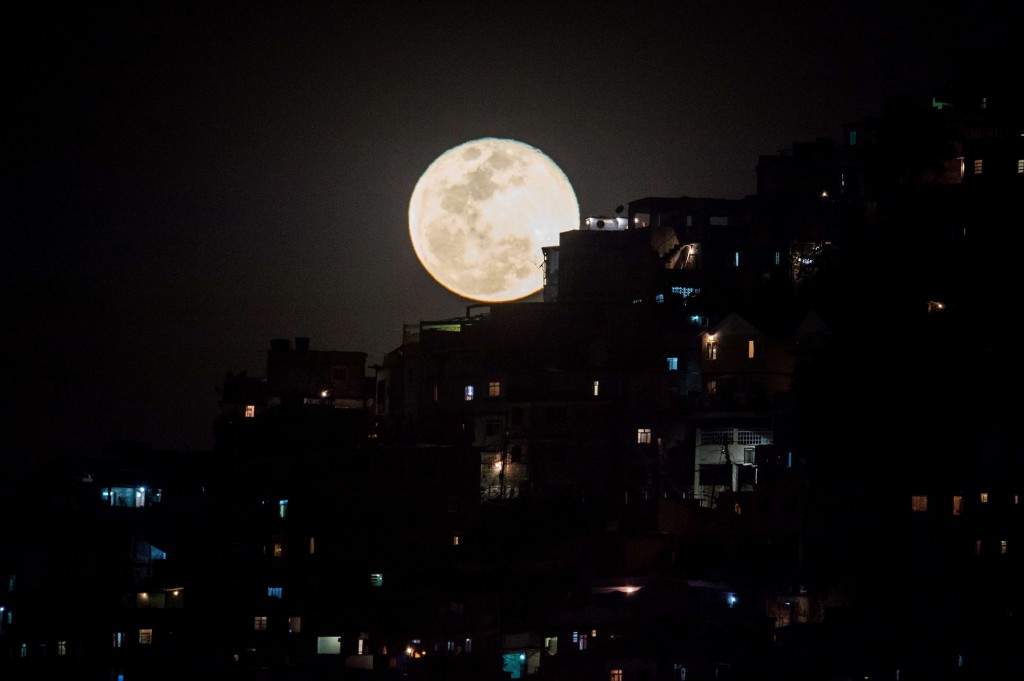 The super moon rises behind Providencia favela in Rio de Janeiro, Brazil. (AFP PHOTO / YASUYOSHI CHIBA)