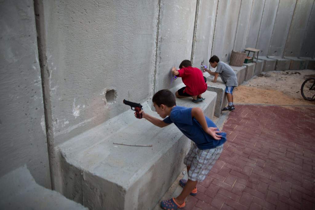 Israeli children hold toy guns as they pretend to play war games next to newly built protection cement walls around a kindergarten in the center of Kibbutz Nahal Oz located near the border with Gaza Strip. (AFP PHOTO/ MENAHEM KAHANA)