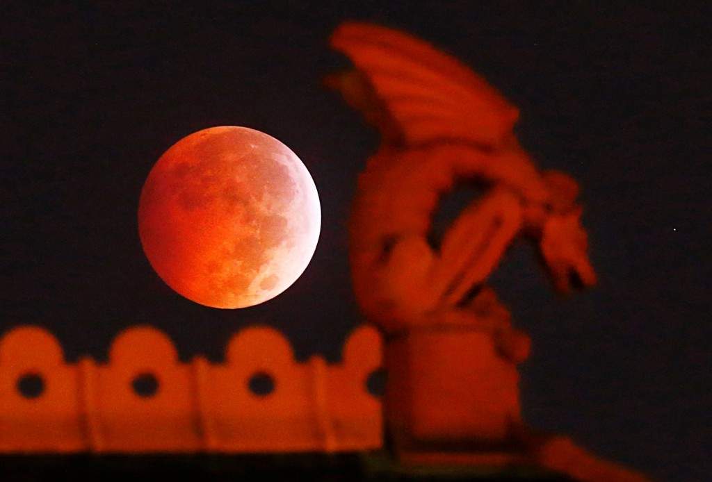 A lunar eclipse appears behind a gargoyle atop the old red Dallas County Courthouse. (AP Photo/The Dallas Morning News, Tom Fox)