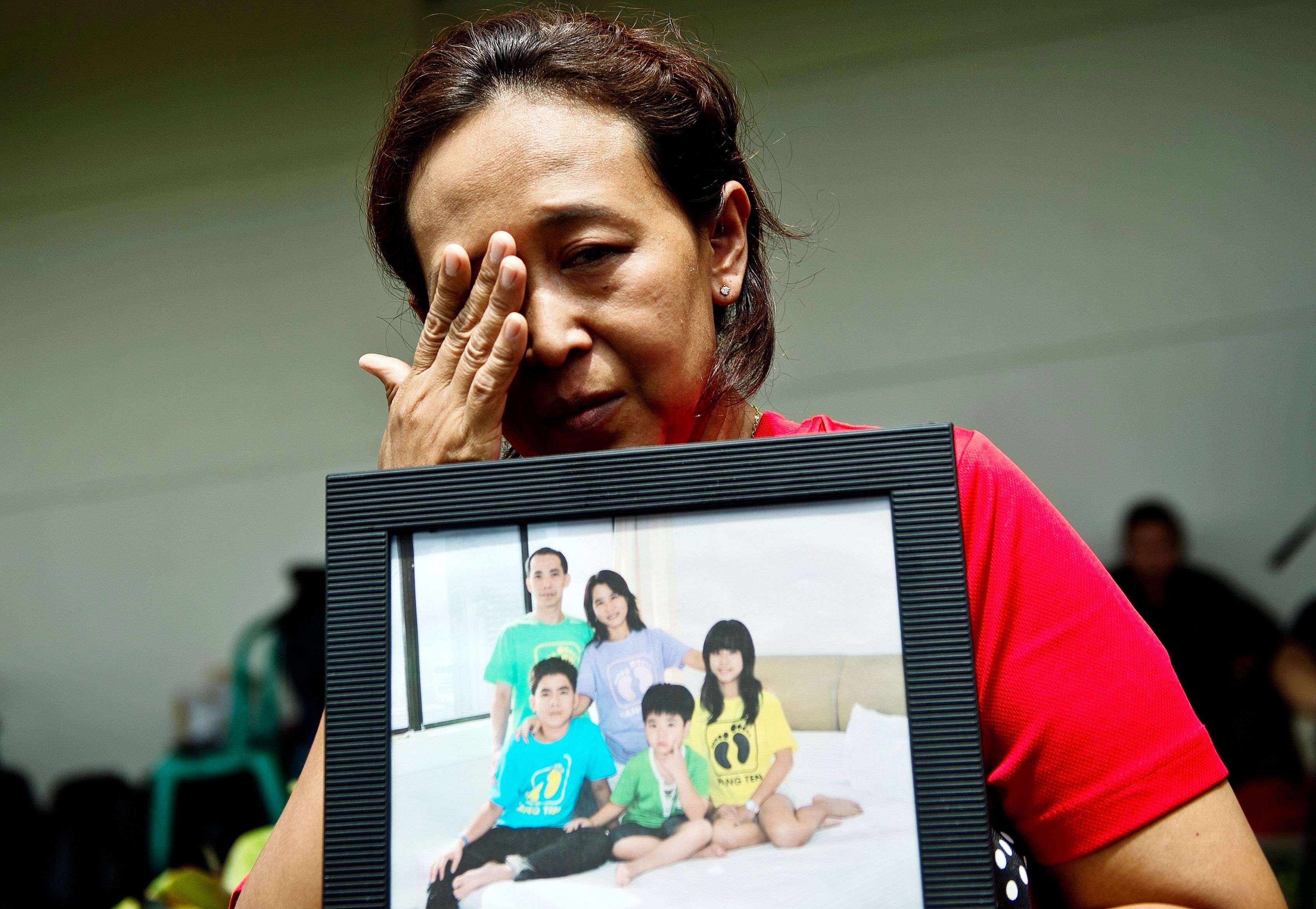 An Indonesian woman wipes her eyes while holding a family picture of passengers onboard the missing Malaysian air carrier AirAsia flight QZ8501. (AFP PHOTO / MANAN VATSYAYANA)