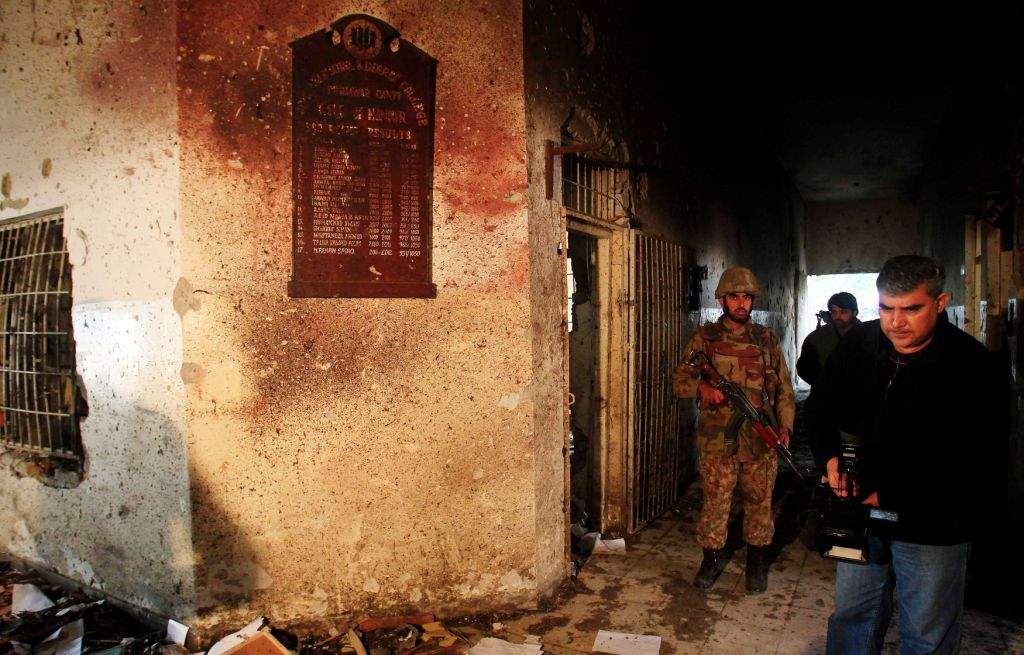 A local cameraman films in front of an army soldier at the Army Public School, which was attacked by Taliban gunmen, in Peshawar. (REUTERS/Fayaz Aziz)