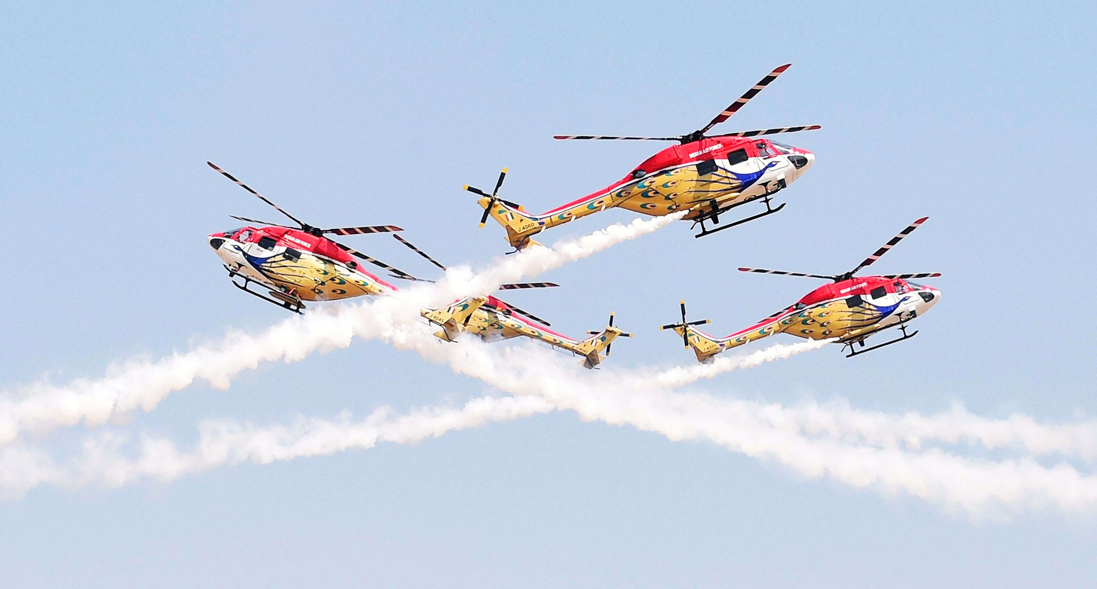Indian Air Forces’ helicopter display team ‘Sarang’ performs during the inauguration of the Aero India event at Yelhanka Air Base in Bengaluru. (Shailendra Bhojak- PTI)