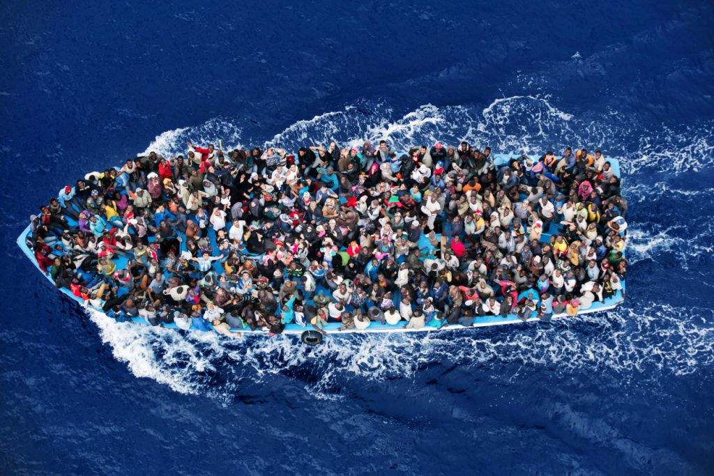This photo shows shipwrecked people are rescued, aboard a boat 20 miles north of Libya, by a frigate of the Italian navy on June 7, 2014. After hundreds of men, women and children had drowned in 2013 off the coast of Sicily and Malta, the Italian government put its navy to work under a campaign called “Mare Nostrum” rescuing refugees at sea. (AP Photo/Massimo Sestini)