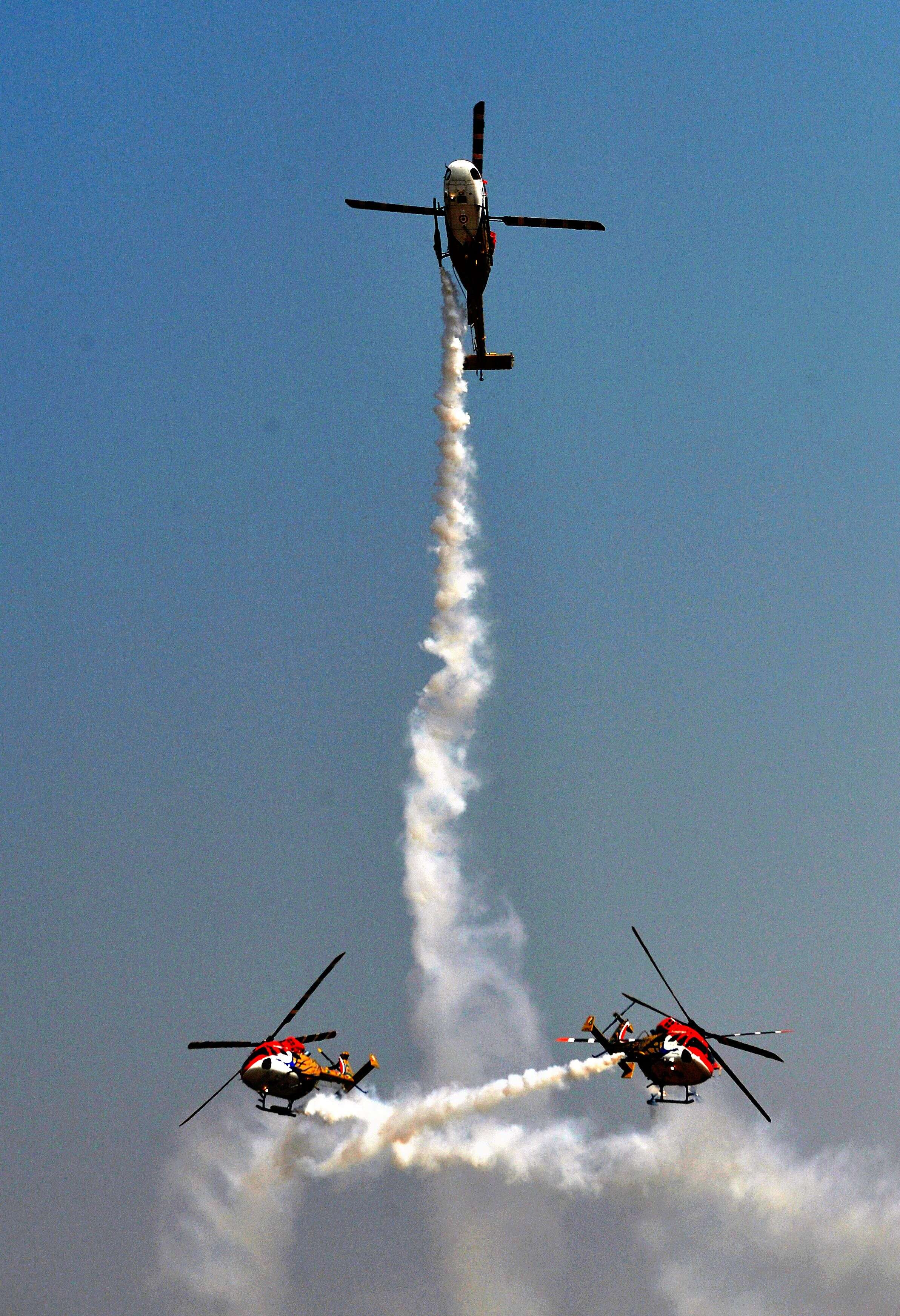 Sarang aerobatics team of the Indian Air Force fly Advanced Light Helicopters (ALH) at Yelahanka Airforce Station in Bangaluru on the inaugural day of Aero India. (Manjunath Kiran – AFP)