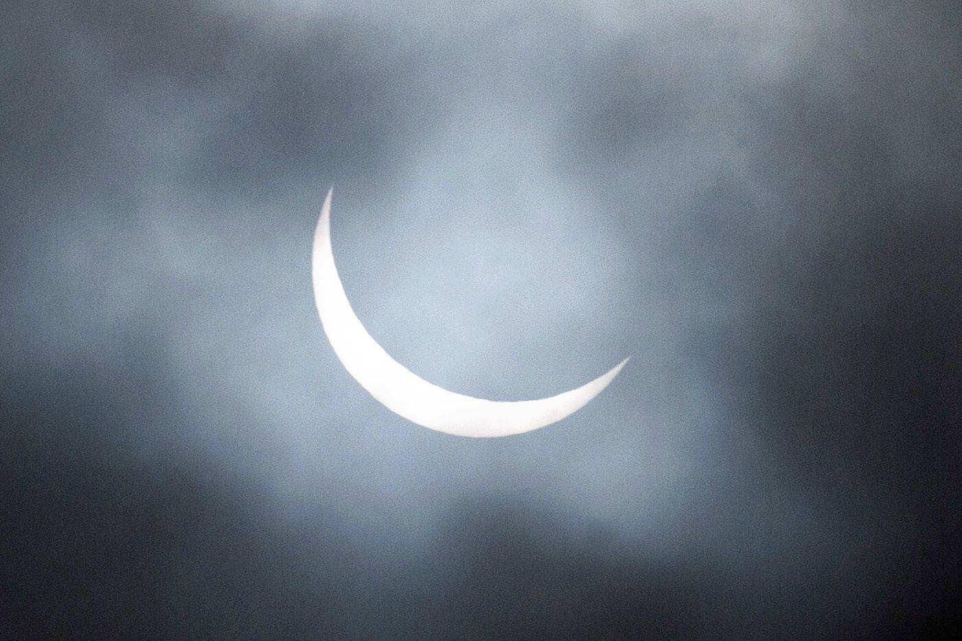 A partial solar eclipse is visible through a break in the cloud cover over Scarborough, Northern England. (AFP PHOTO / OLI SCARFF)