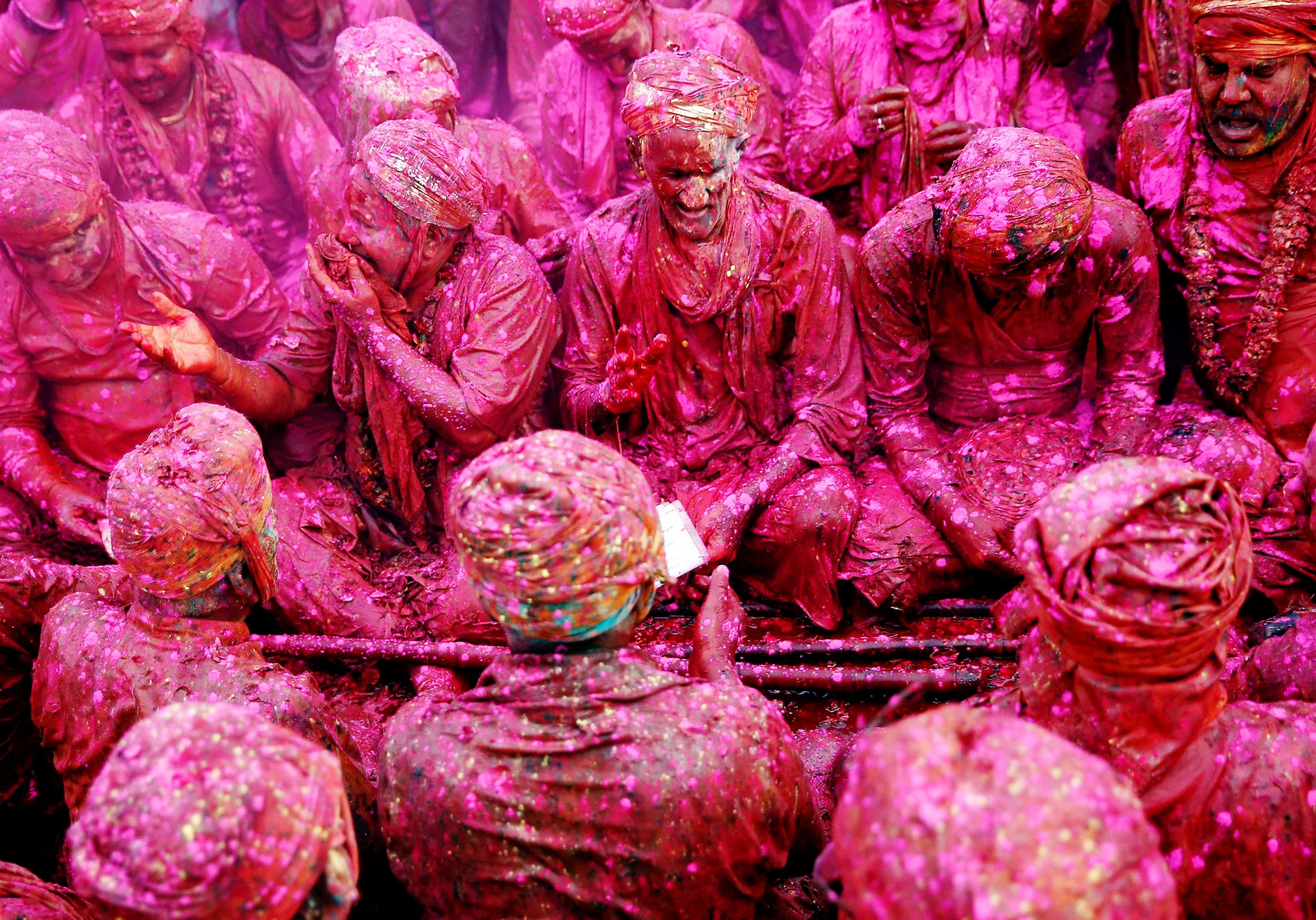 Men daubed in colours sing religious songs as they celebrate "Lathmar Holi" at Nandgaon