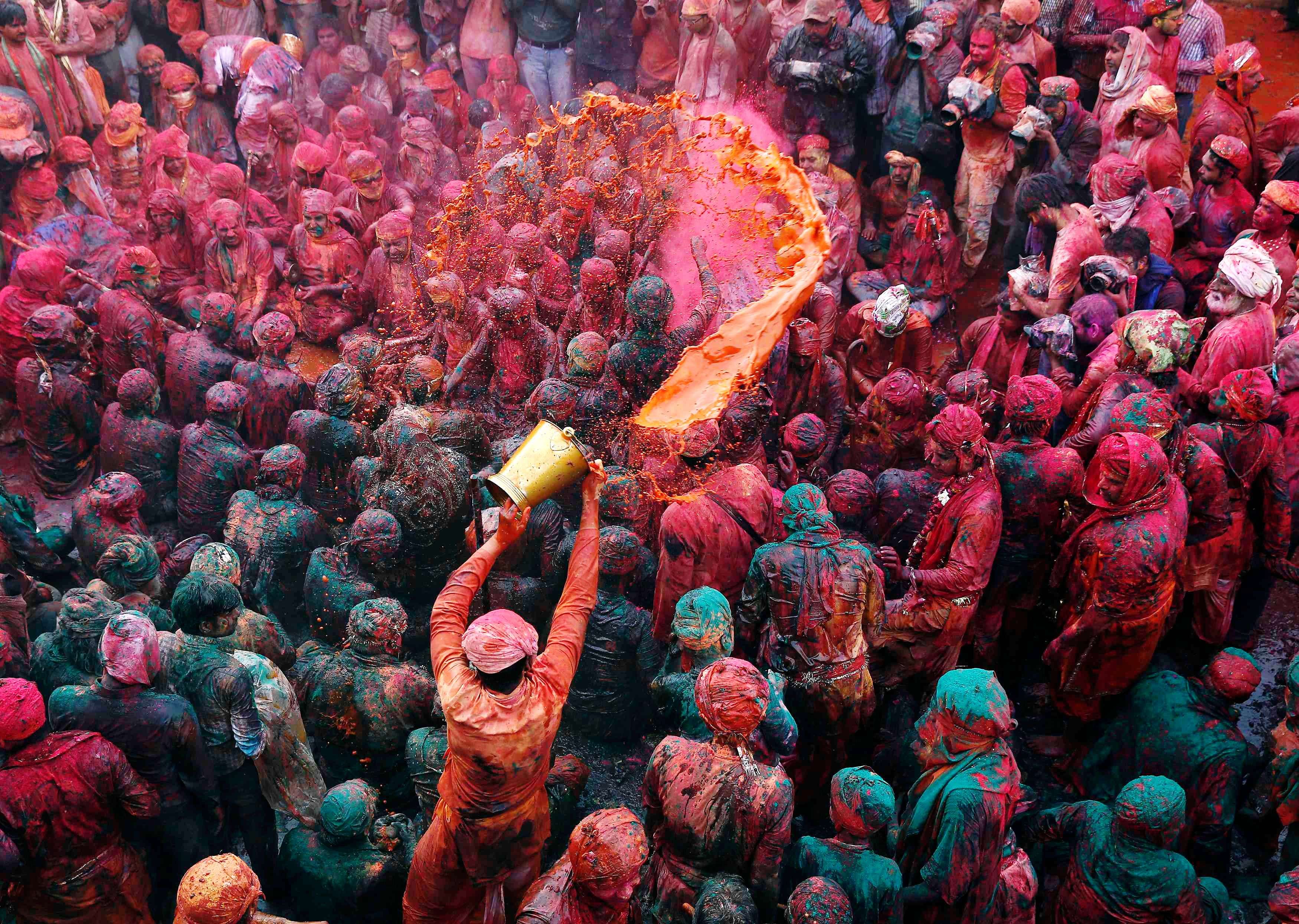 A man throws coloured water as he celebrates "Lathmar Holi" at Nandgaon
