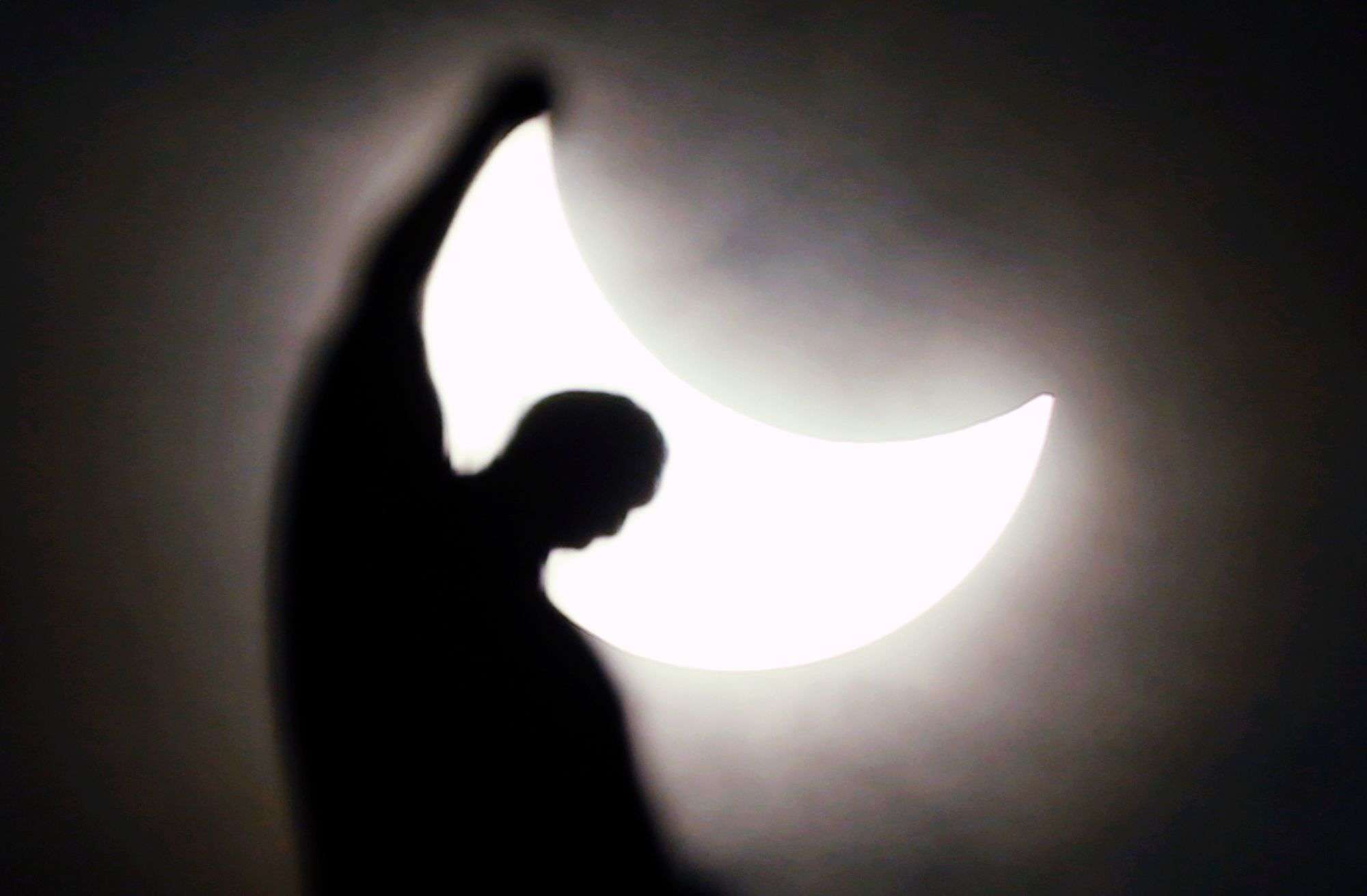 The moon starts to block the sun during a solar eclipse over a statue of the Duomo gothic cathedral in Milan, Italy. (AP Photo/Luca Bruno)