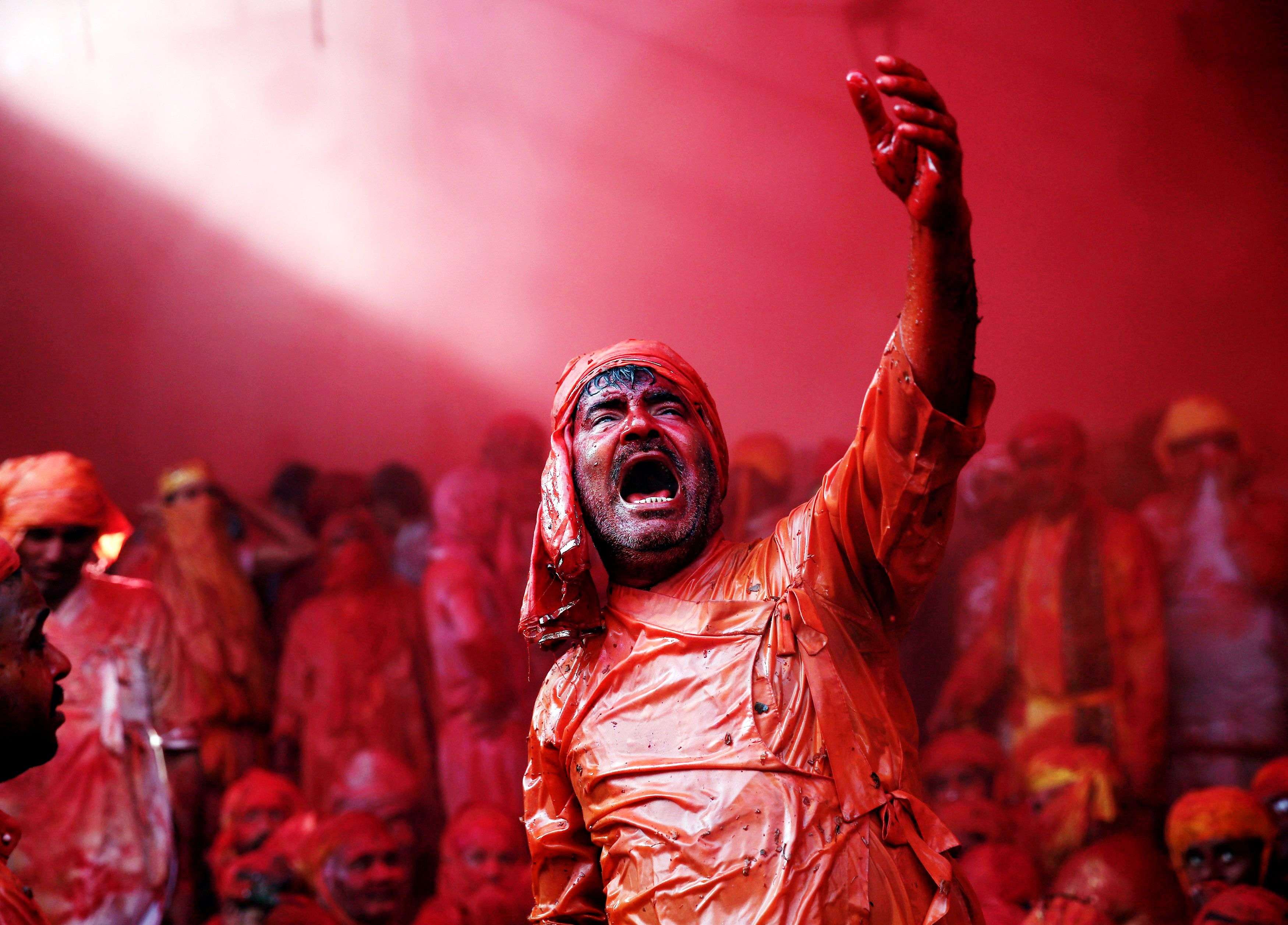 A man daubed in colours sings religious songs as he celebrates Lathmar Holi at Barsana