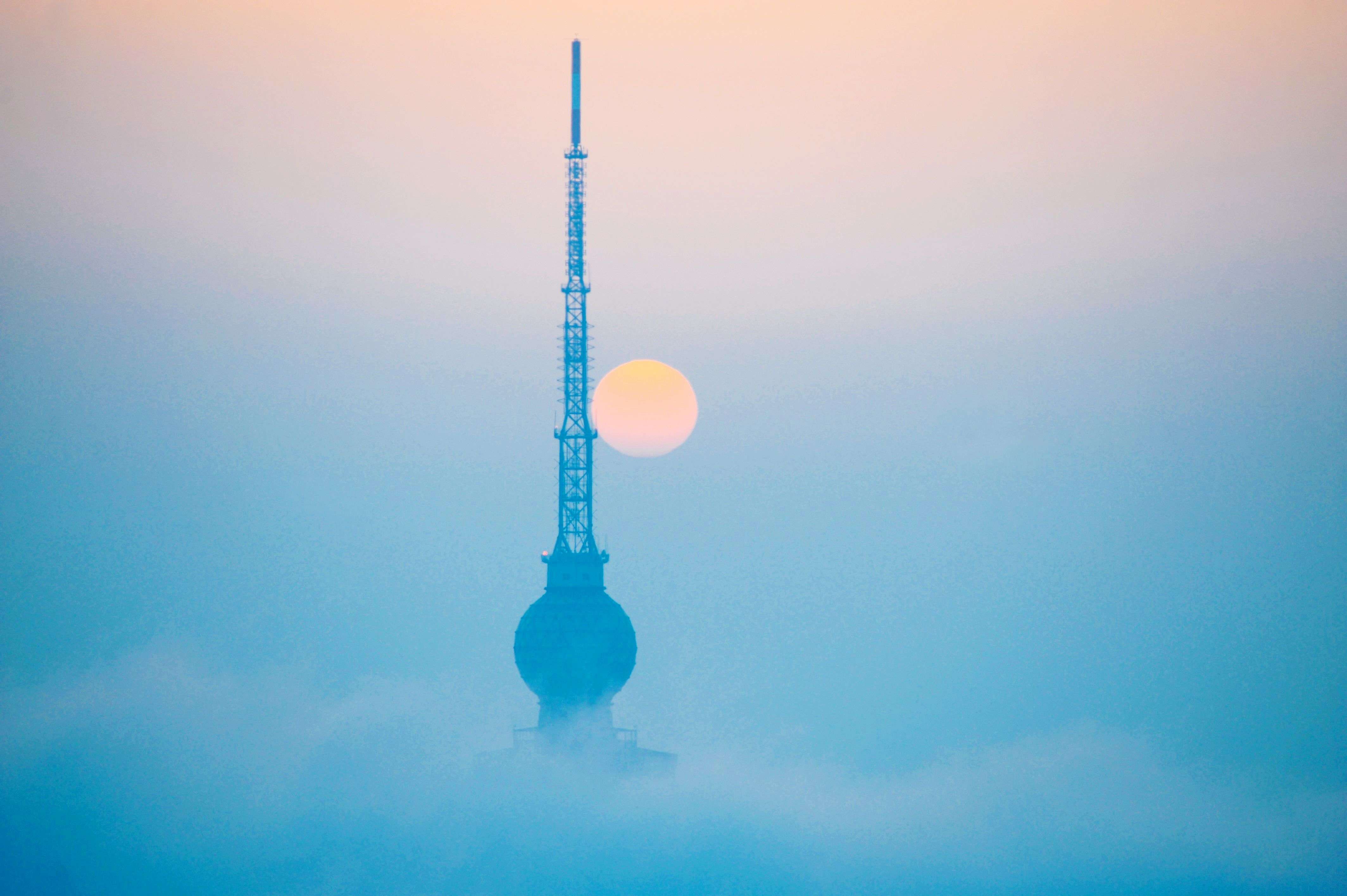 This photo shows the top of a tower looming out of heavy fog in Qingdao, east China's Shandong province. Falls in Chinese housing prices decelerated in March from the previous month, a survey showed on March 31, after authorities loosened mortgage and tax policies as growth in the world's second-largest economy slows. (AFP photo)