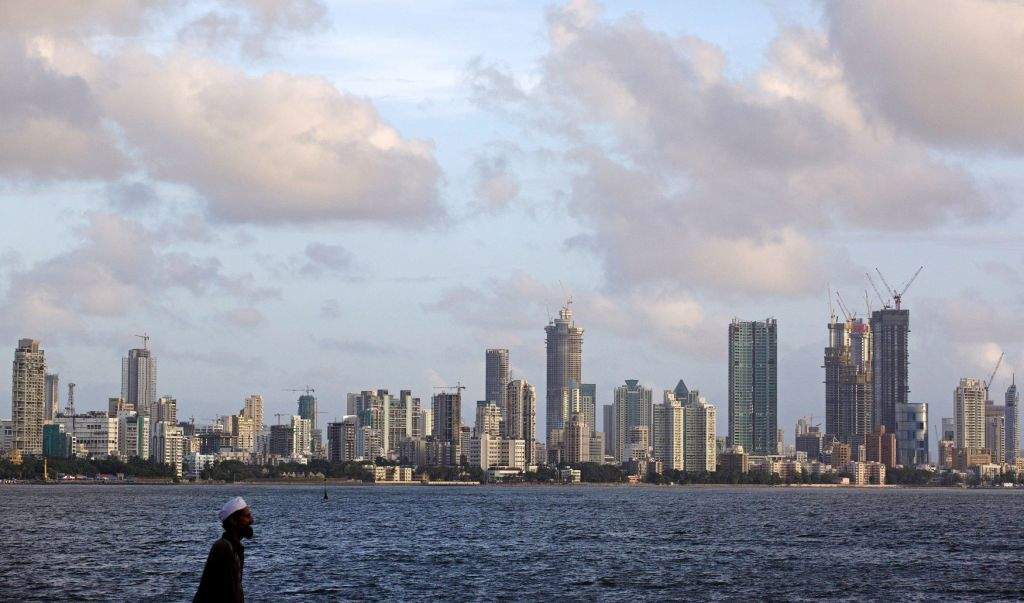 A man walks at the seafront as scattered clouds are seen over Mumbai's skyline. (REUTERS/Danish Siddiqui)