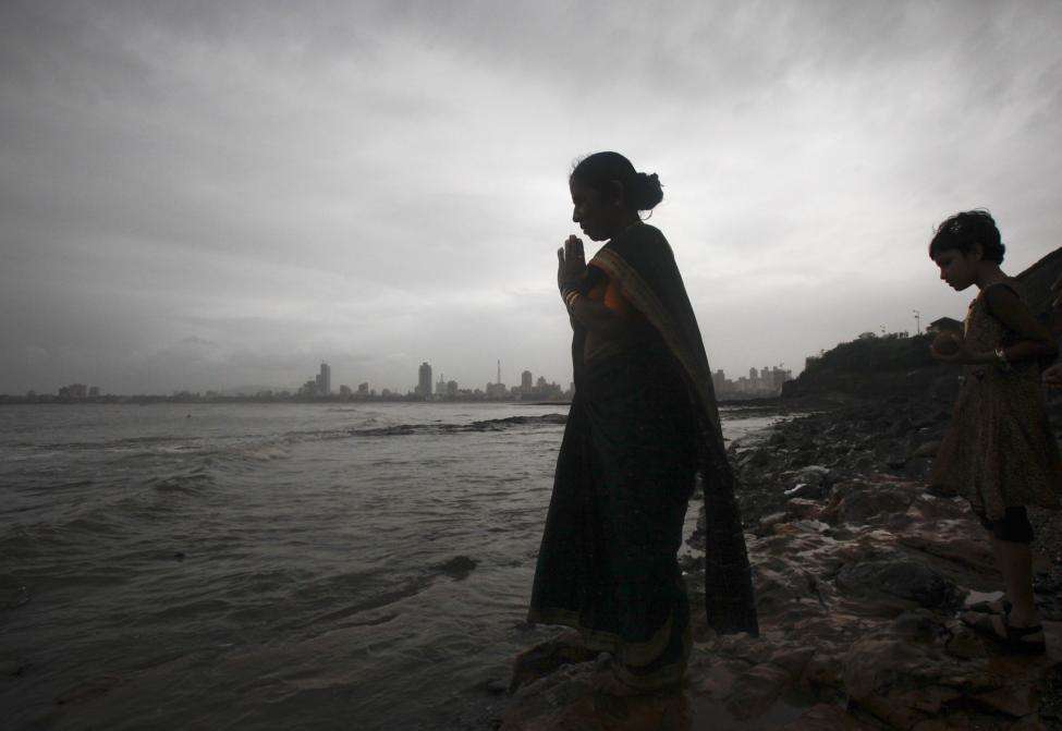 A woman is silhouetted against the Mumbai skyline as she performs prayers seaside to celebrate Narali Purnima or coconut festival. (REUTERS/Danish Siddiqui/Files)