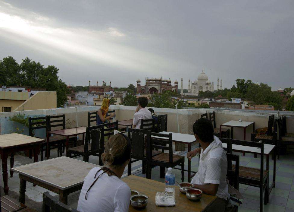 Tourists turn to look at the historic Taj Mahal while dining at a rooftop restaurant near the monument in Agra. (REUTERS/Adeel Halim/Files)