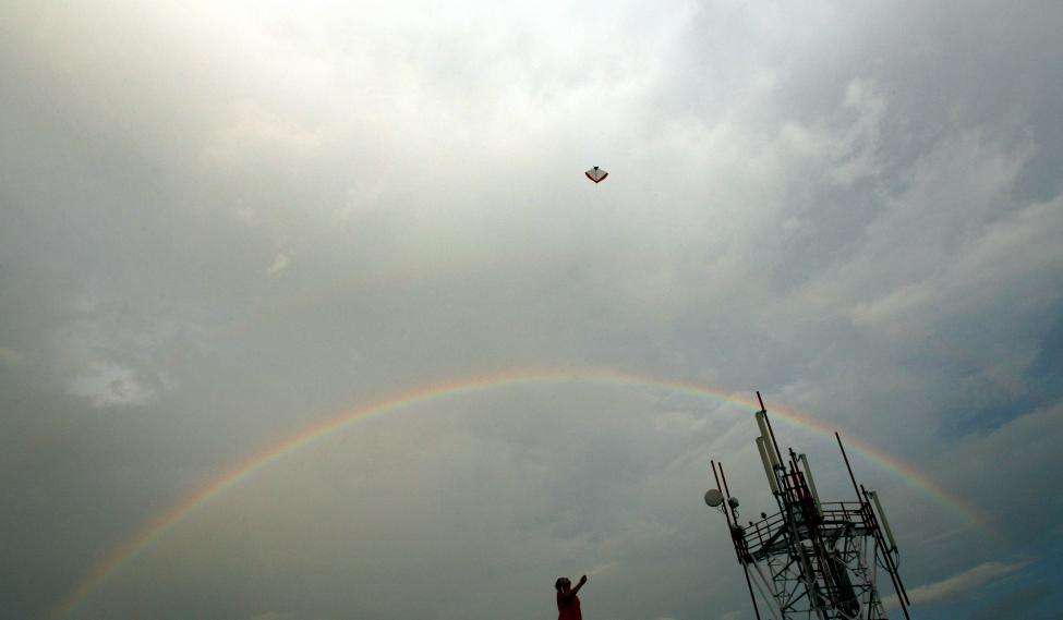 An Indian boy flies a kite as a rainbow is seen over the skyline in New Delhi. (REUTERS/Adnan Abidi/Files)