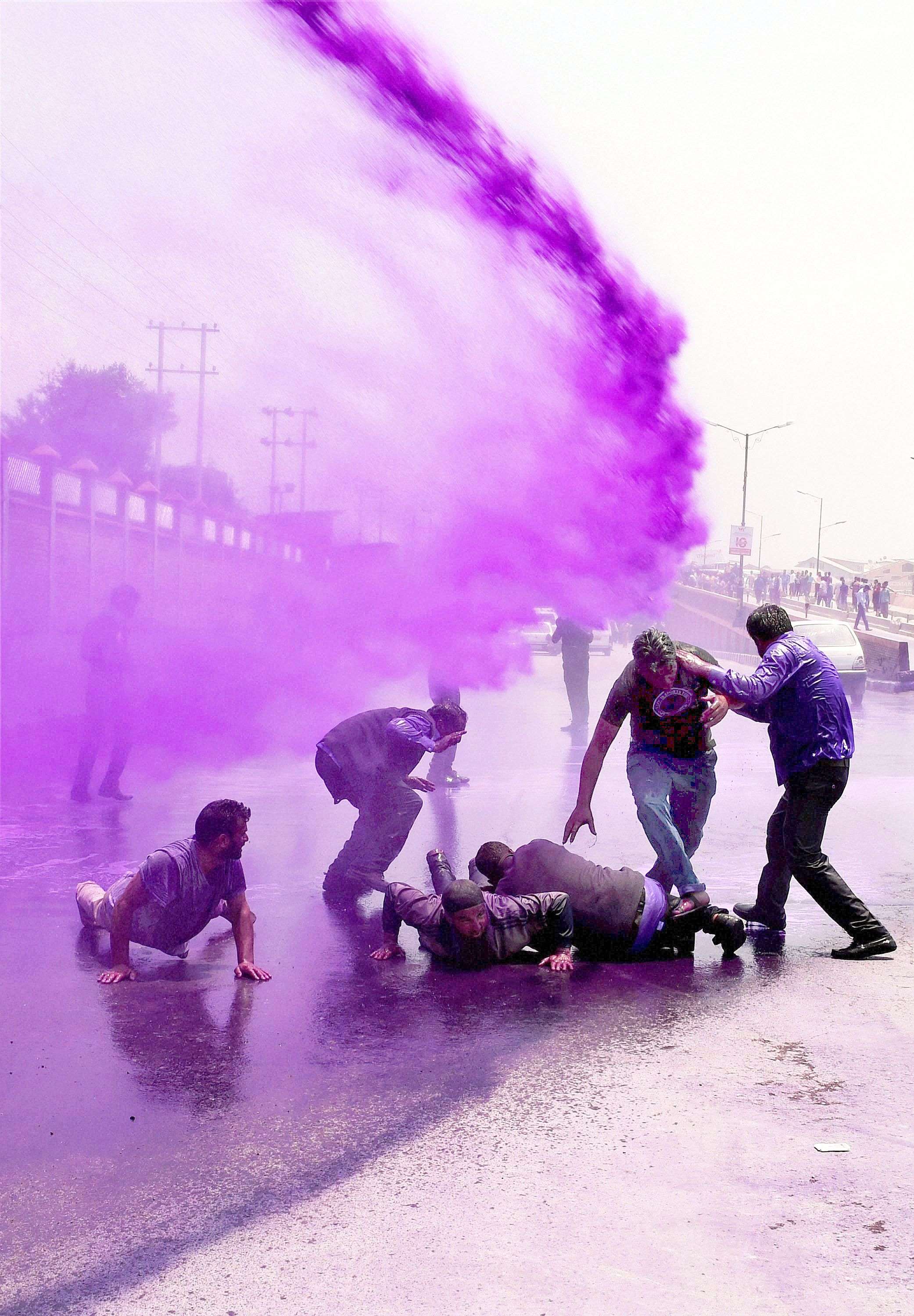 Colored water from water cannons hit Kashmiri government employees during a protest in Srinagar, India. Police detained dozens of government employees who protested demanding regularization of contractual jobs and a hike in salary.(AP/Mukhtar Khan) 