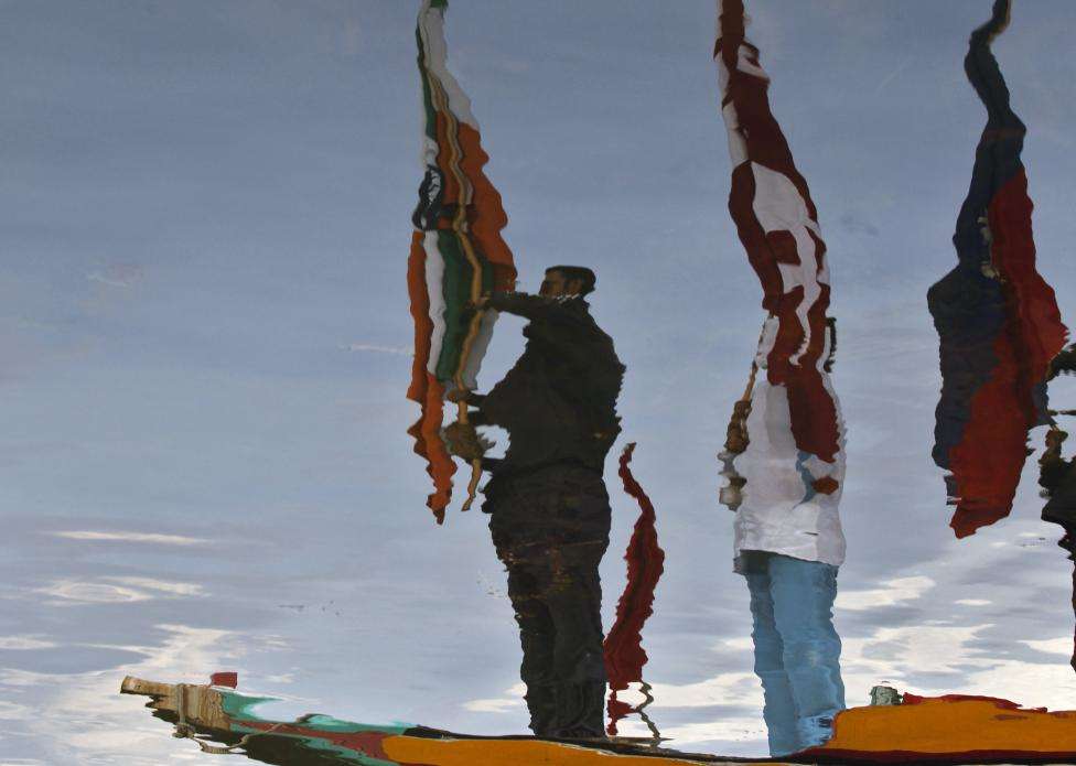 Participants carrying flags are reflected in the waters of Dal Lake during the opening ceremony of "Jashan-e-Dal" in Srinagar. The picture is rotated 180 degrees clockwise. (REUTERS/Fayaz Kabli/Files)