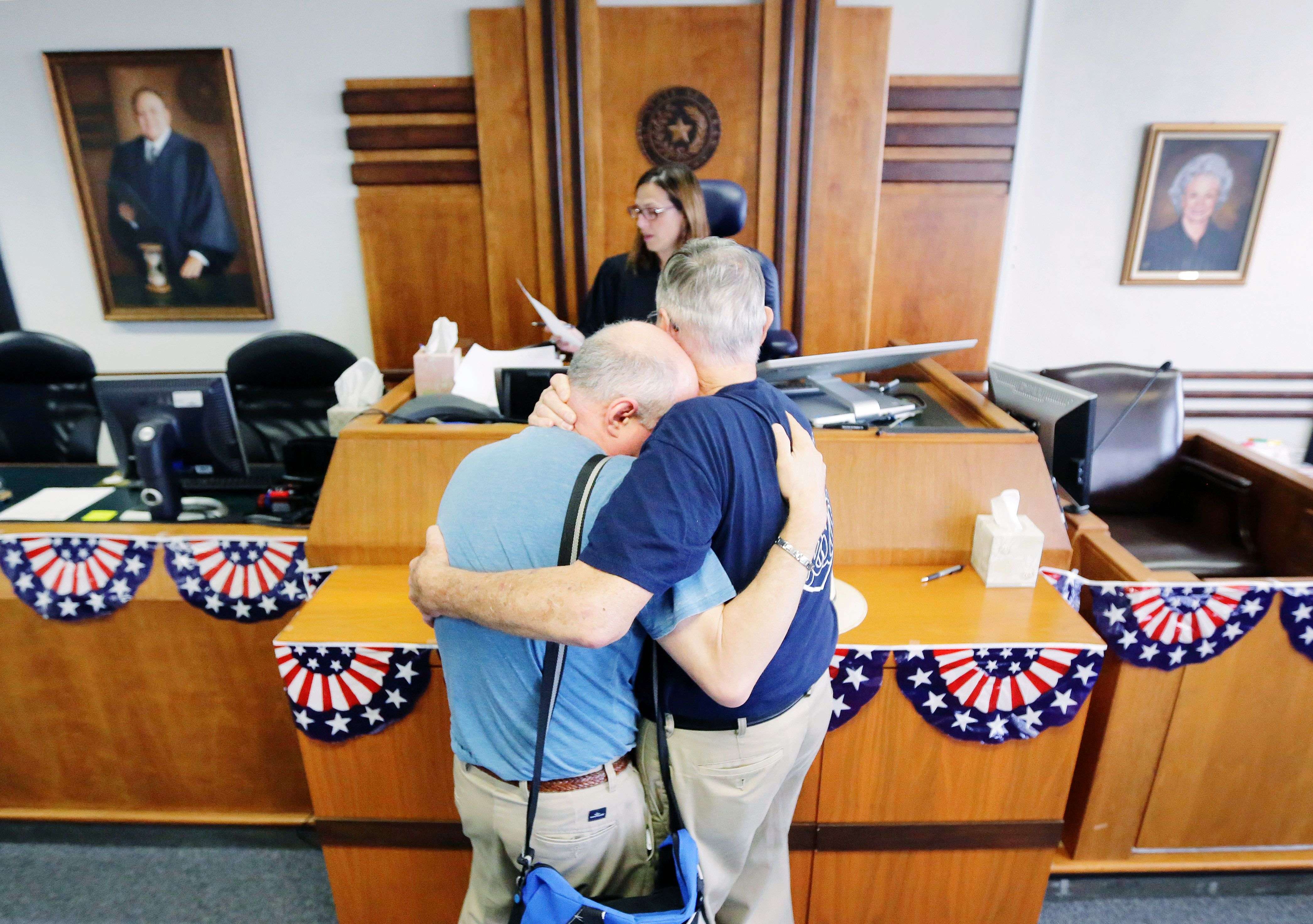 Gerald Gafford, right, comforts his partner of 28 years, Jeff Sralla, left, as they stand before Judge Amy Clark Meachum to obtain a time waiver at the Travis County Courthouse in Austin, Texas after the US Supreme Court ruled that same-sex couples have the right to marry nationwide. Sralla broke into tears as the judge approved the waiver allowing the couple to get married this weekend. (AP Photo/Eric Gay)