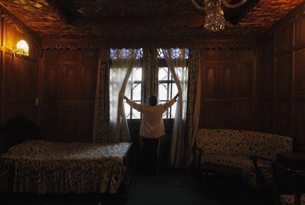 A waiter adjusts the curtains in a room of a houseboat in Srinagar. For nearly a century, hand-carved houseboats bobbing on a placid lake drew millions of visitors including George Harrison, businessman Nelson Rockefeller and actress Joan Fontaine to the stunningly beautiful Himalayan region of Kashmir. (REUTERS/Fayaz Kabli/Files)