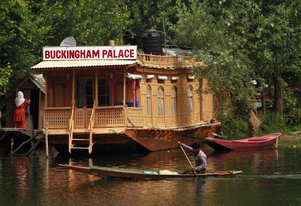 A Kashmiri man rows a Shikara in front of a houseboat named "Buckingham Palace" on the waters of Dal Lake in Srinagar. (REUTERS/Fayaz Kabli/Files)