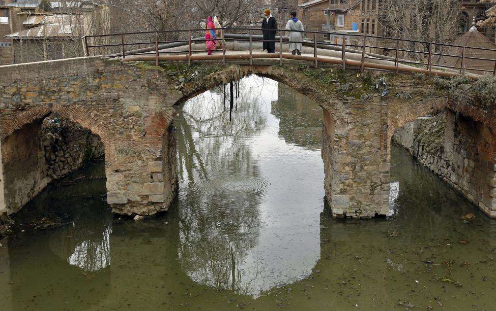 People cross the old Nayidyar bridge over the extension of Dal Lake in the old part of Srinagar. (REUTERS/Fayaz Kabli/Files)