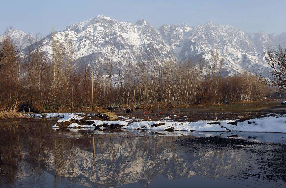 Framed by the Zabarwan Hills, a Kashmiri man sits by Dal Lake on a sunny day, in Srinagar. (REUTERS/Danish Ismail/Files)
