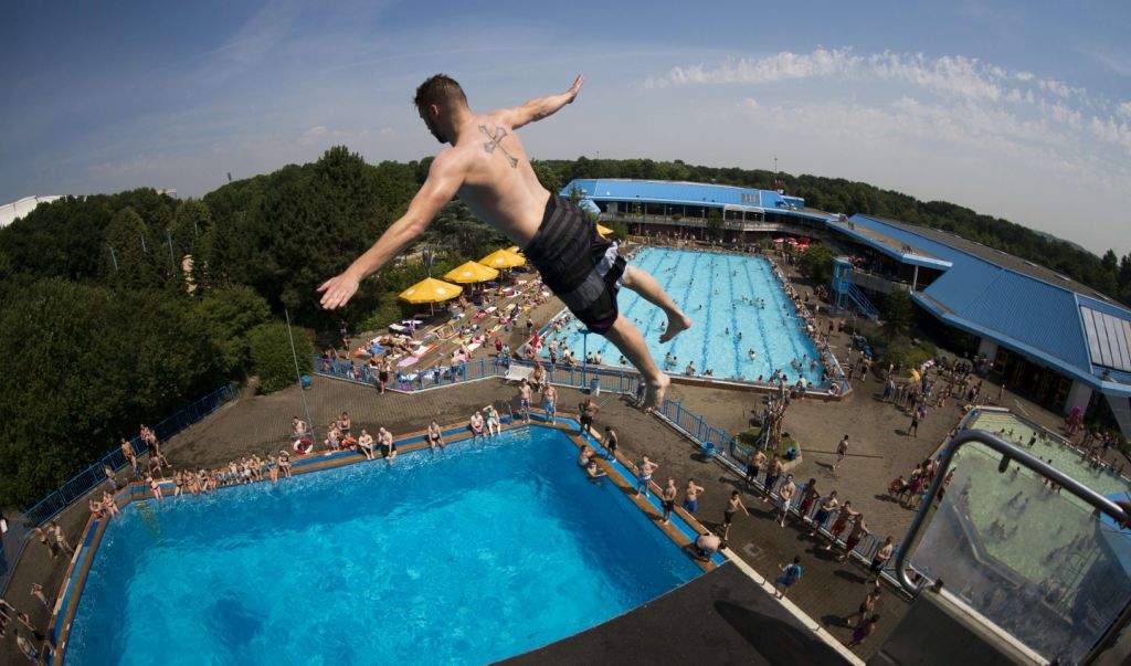 Mario jumps from a diving platform into the water of the 'Sport Paradies' public open air swimming pool in Gelsenkirchen, western Germany. Temperatures in the region reached up to 35 degrees Celsius. (AFP PHOTO / DPA / MARCEL KUSCH)