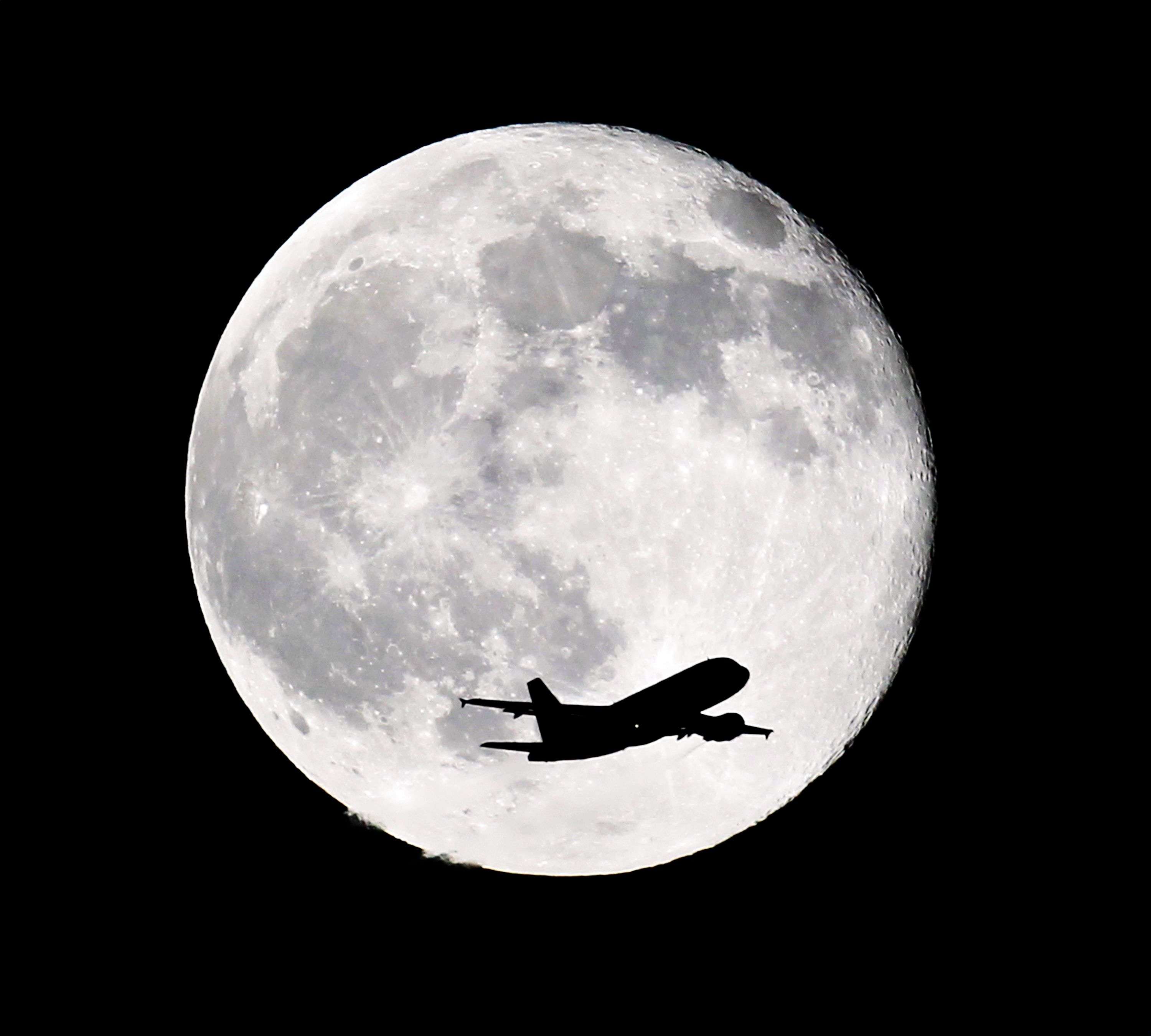 An American Airlines passenger airplane from Miami crosses a blue moon over Whittier, Calif., as it heads to Los Angeles Airport, Friday, July 31, 2015. (AP Photo/Nick Ut)