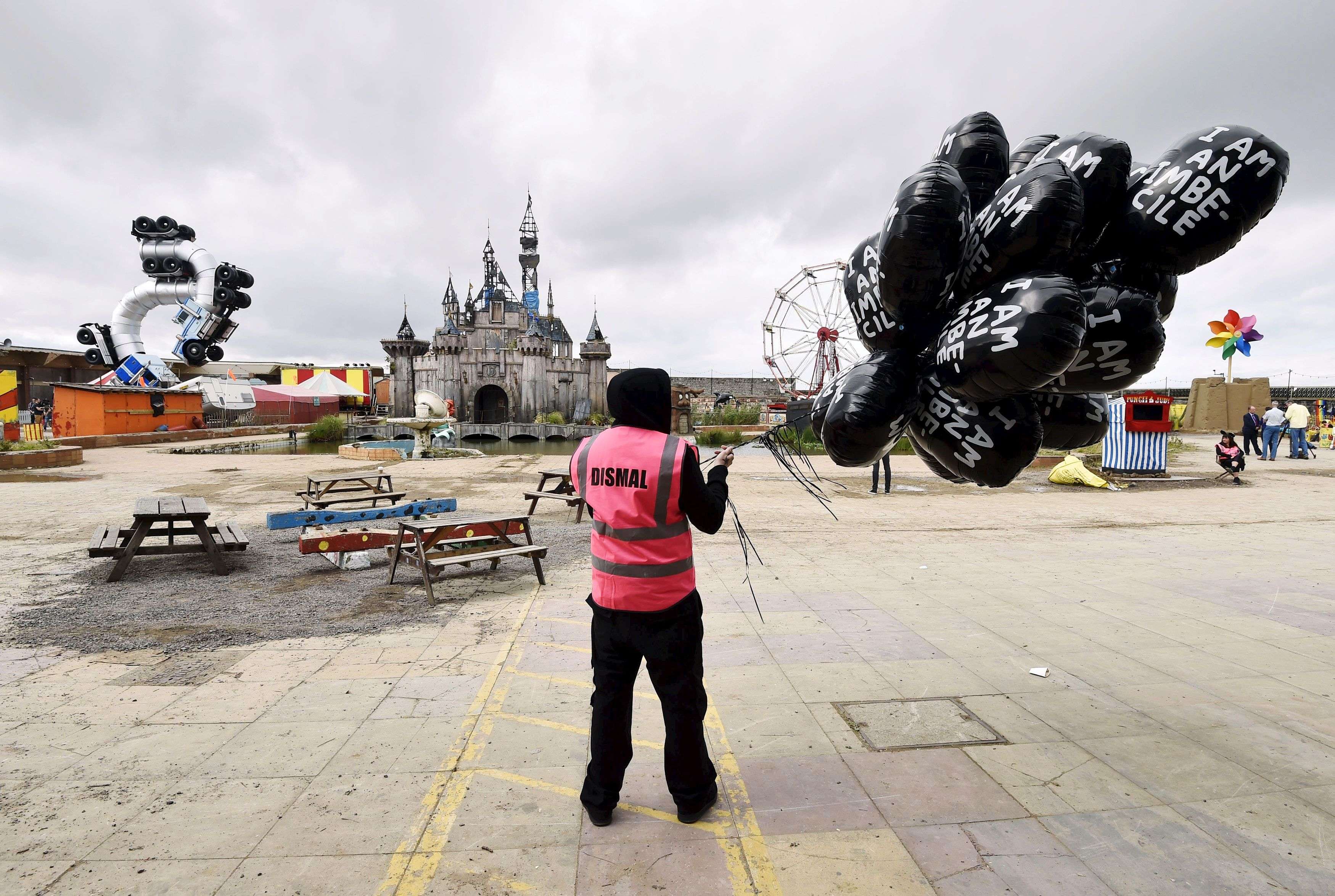 A performer holds a bunch of balloons at 'Dismaland', a theme park-styled art installation by British artist Banksy, at Weston-Super-Mare in southwest England, Britain, August 20, 2015. REUTERS/Toby Melville