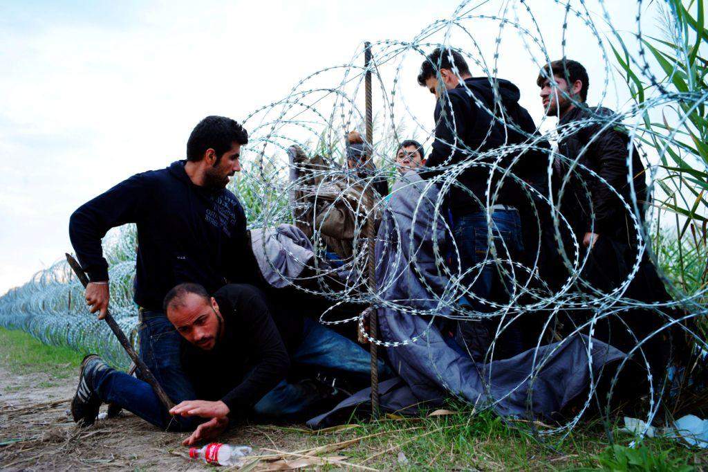 FILE - In this Aug. 26, 2015, file photo, Syrian refugees cross into Hungary underneath the border fence on the Hungarian - Serbian border near Roszke, Hungary. From the three-year-old boy who washed ashore on a Turkish beach to the 71 migrants who suffocated in a truck in Austria to the daily scenes of chaos unfolding in European cities as governments try to halt a human tide heading north. There is no let up to the horrors that Syria’s civil war keeps producing. Syria’s brutal conflict, now in its fifth year, has touched off the greatest humanitarian crisis of our time. About 250,000 people have been killed and more than one million wounded since March 2011, according to U.N. officials. (AP Photo/Bela Szandelszky, File)