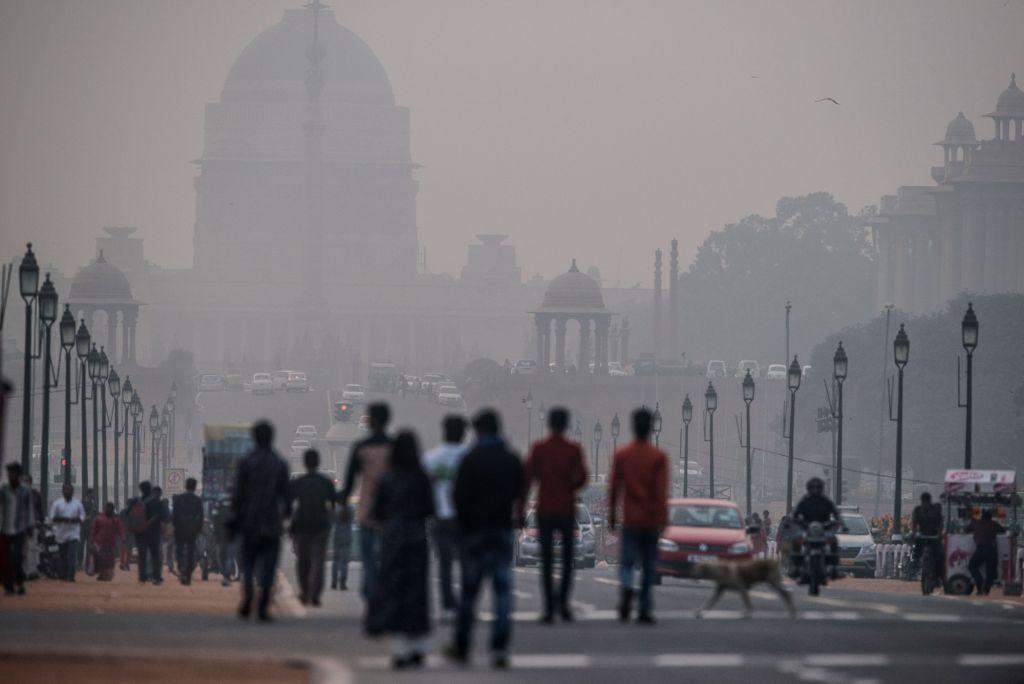 Indian pedestrians walk near smog enveloped government offices on Rajpath in New Delhi on December 1, 2015.  India's capital, with 18 million residents, has the world's most polluted air with six times the amount of small particulate matter (pm2.5) than what is considered safe, according to the World Health Organization (WHO). The air's hazardous amount of pm2.5 can reach deep into the lungs and enter the blood, causing serious long term health effect, with the WHO warning India has the world's highest death rate from chronic respiratory diseases. India, home to 13 of the world's top 20 polluted cities, is also the third largest emitter of greenhouse gases behind the United States and China.  Rich countries should not force the developing world to abandon fossil fuels completely, Indian Prime Minister Narendra Modi said at the UN climate summit in Paris on December 1. Almost a third of India's population remains in severe poverty with limited access to electricity, and its government sees little chance of boosting their prospects without turning to cheap and plentiful coal.   AFP PHOTO / ROBERTO SCHMIDT