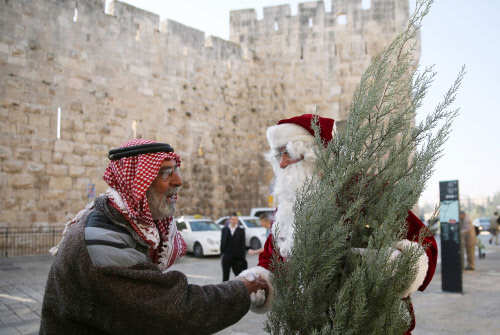 A Palestinian Christian man dressed up as Santa Claus greets  people in Jerusalem (Photo Courtesy: Gali Tibbon / AFP)