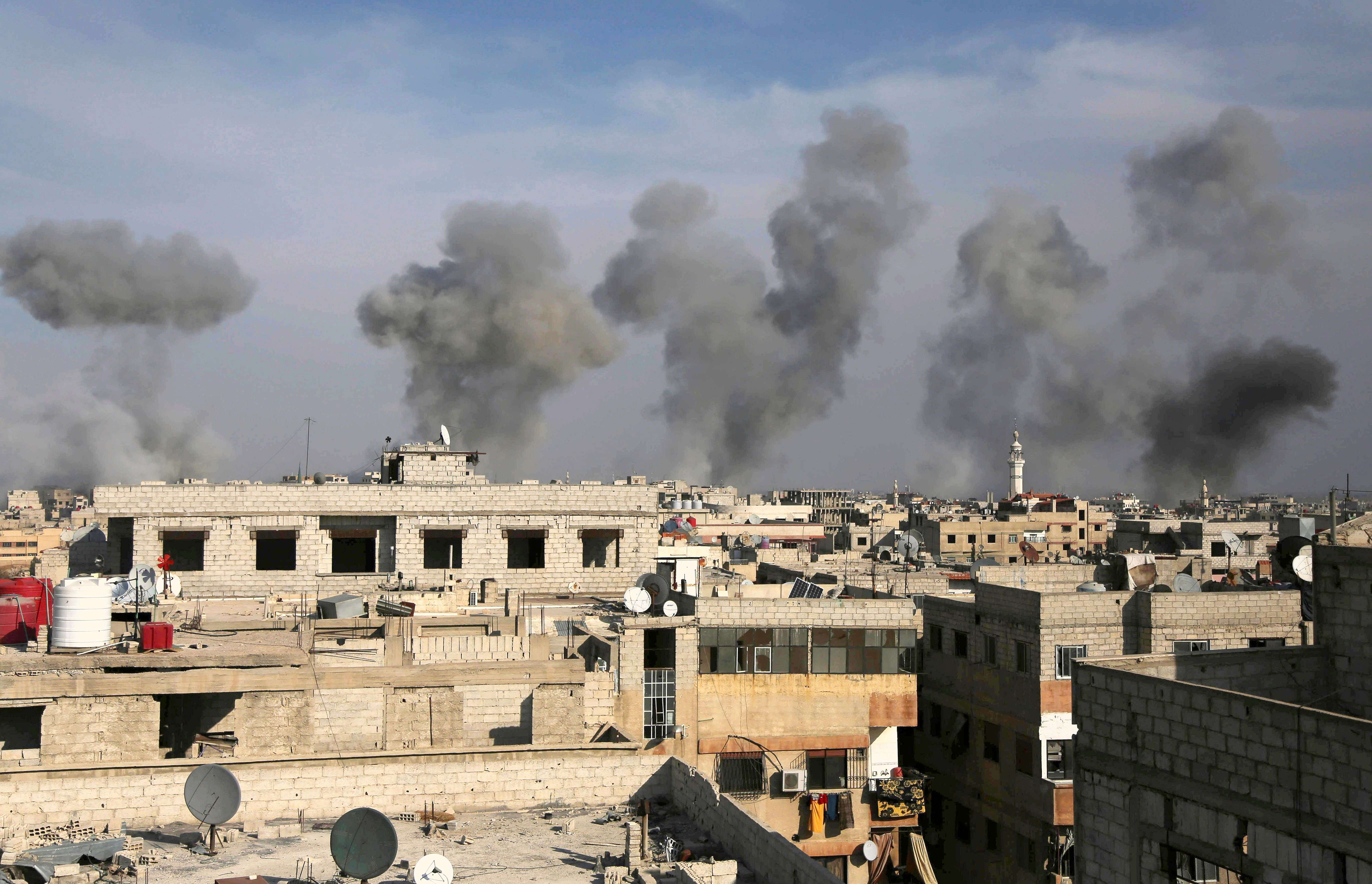 TOPSHOT - Smoke billows after air strikes by regime forces on the town of Douma in the eastern Ghouta region, a rebel stronghold east of the capital Damascus, on December 13, 2015. At least 31 civilians were killed in heavy bombardment of a besieged Syrian rebel stronghold, including near a school in Douma, east of Damascus, the Syrian Observatory for Human Rights said. AFP PHOTO / AMER ALMOHIBANY / AFP / AMER ALMOHIBANY