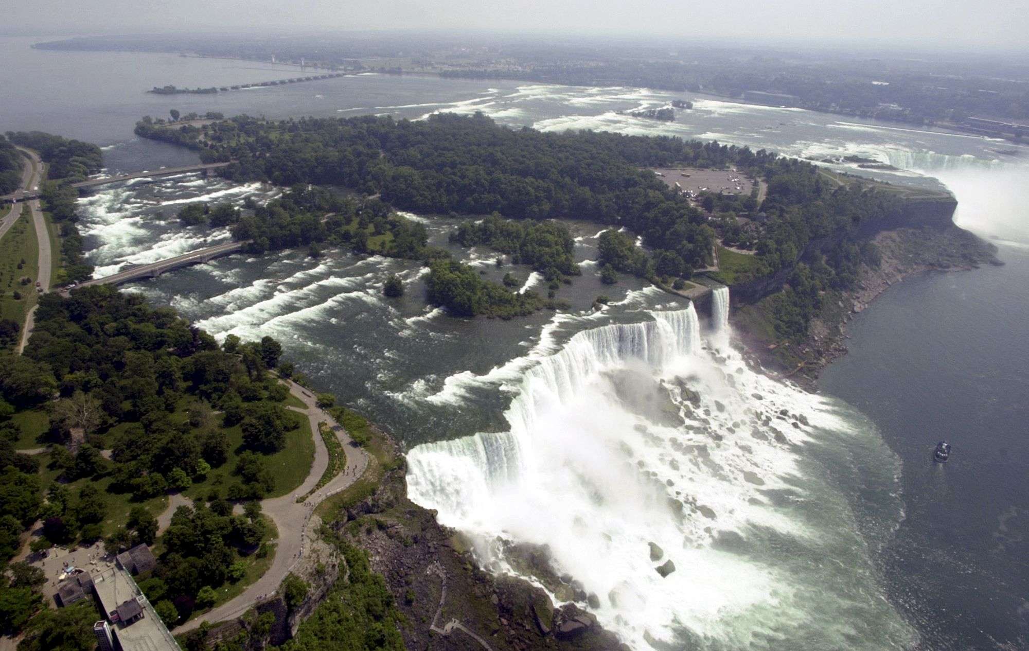 FILE - In this June 14, 2001, file aerial photo, the United States side, foreground, of Niagara Falls is viewed in Niagara Falls, N.Y. New York officials are considering temporarily turning Niagara Falls into a trickle. State officials are holding a public hearing this week to discuss plans for replacing 115-year-old bridges, left, linking the mainland to islands near the brink of the falls. To do so, they might reduce the flow on the American side of the falls by building a temporary structure to redirect Niagara River water to the Canadian side, upper right. (AP Photo/David Duprey, File) Summary
