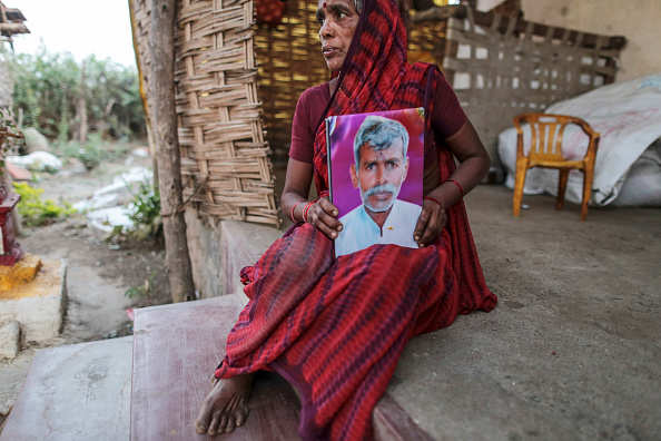 Shobha Singh Bais sits for photograph while holding an image of her deceased husband Govind outside her house in Yavatmal, Maharashtra, India, on Tuesday, Feb. 3, 2015. In a country where as many as one in three of the world's suicides occur, about 12 farmers a day kill themselves in Maharashtra, the second-largest state, and the numbers are growing, farmer lobby group data show. A global cotton surplus has sent prices tumbling and aggravated rural poverty in India. Photographer: Dhiraj Singh/Bloomberg via Getty Images
