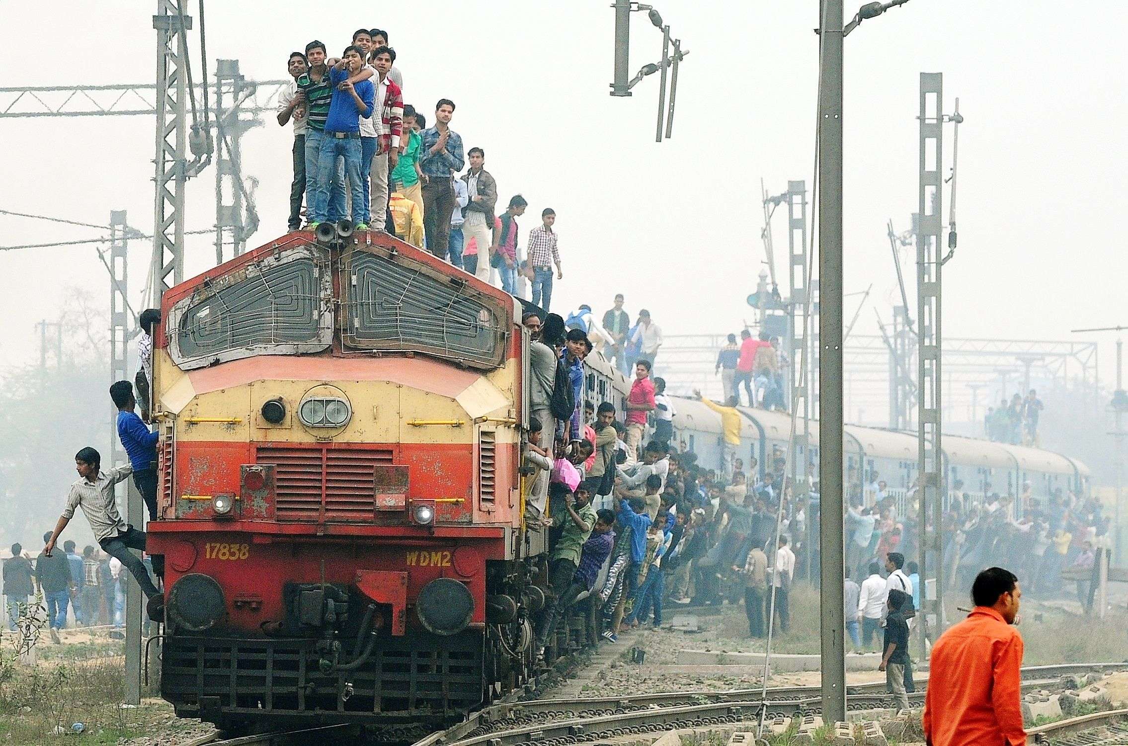 Indian passengers stand and hang onto a train as it departs from a station on the outskirts of New Delhi on February 25, 2015.  Indian Railways Minister Suresh Prabhu is scheduled to present the railway budget to parliament on February 26.    AFP PHOTO/MONEY SHARMA