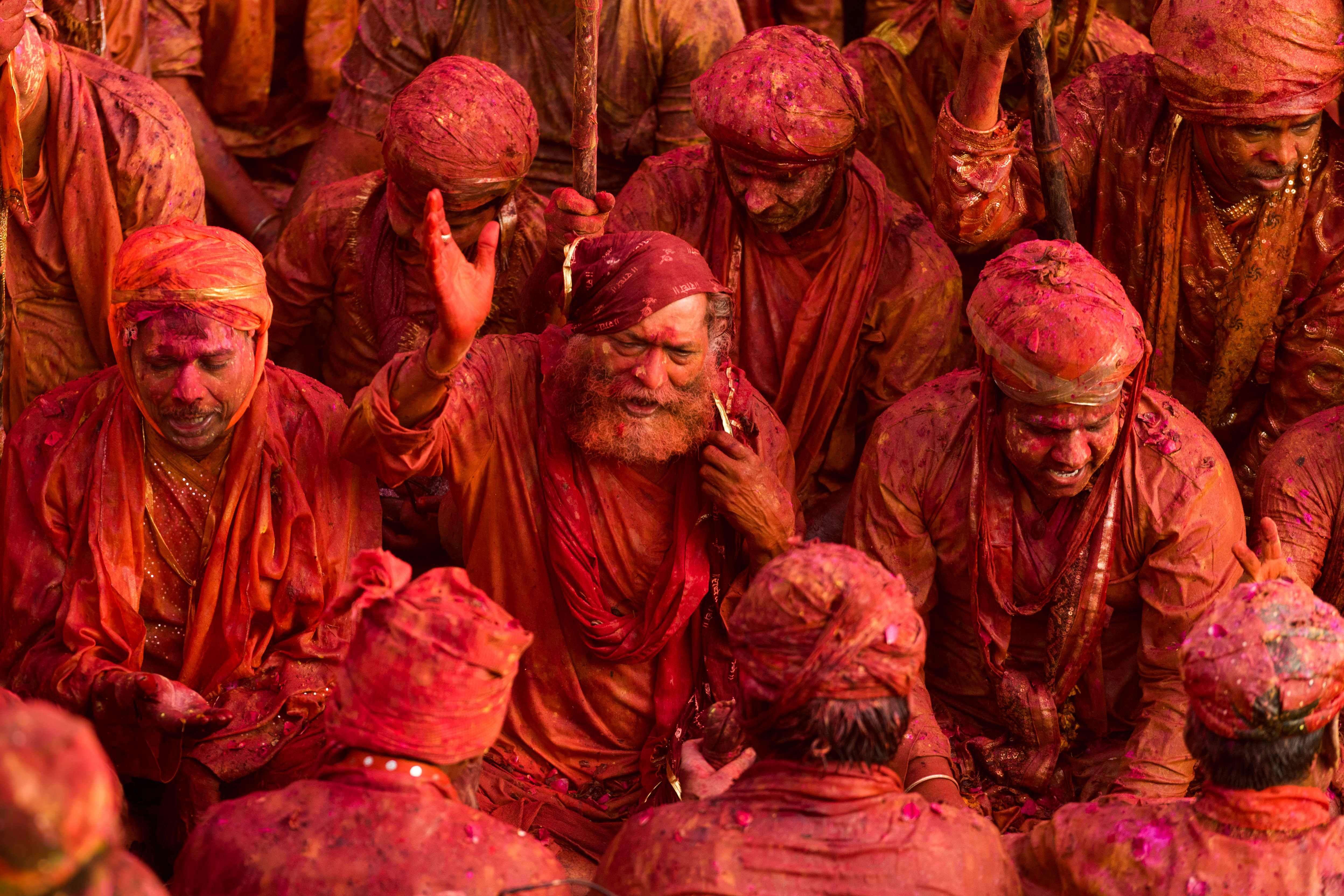 Indian revellers covered in coloured powder sit inside a temple during prayers held as part of the Lathmar Holi celebrations in the village of Nandgaon on March 18, 2016.  Holi, also called the Festival of Colours, is a popular Hindu spring festival observed in India at the end of the winter season on the last full moon day of the lunar month. / AFP PHOTO / Francois Xavier MARIT