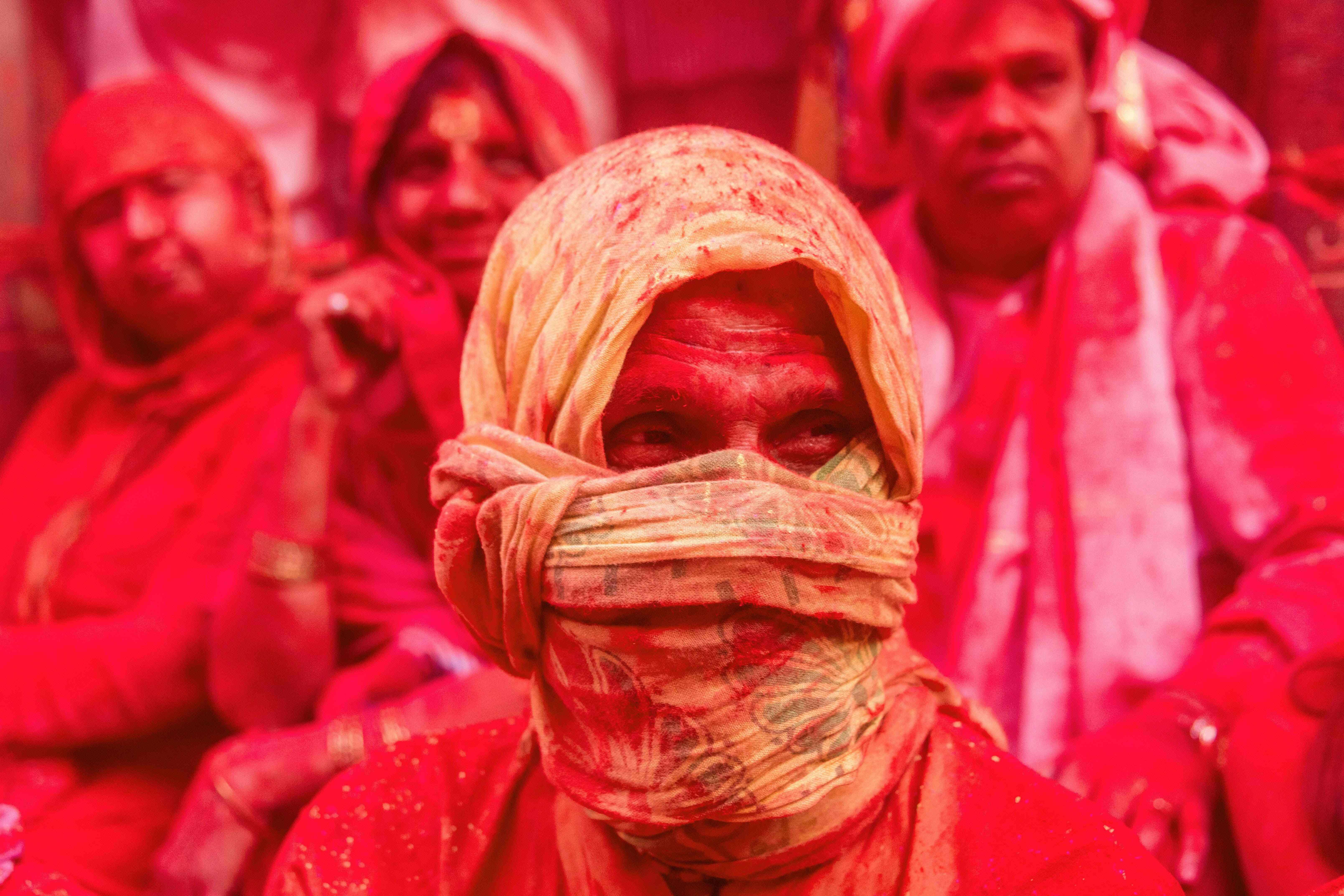 TOPSHOT - Indian villagers are covered in coloured powder during the Lathmar Holi festival at the Radha Rani temple in Barsana, some 130kms from New Delhi on March 16, 2016.  During the Lathmar Holi festival, the women of Barsana, the legendary hometown of Radha, consort of Hindu God Krishna, attack the men from Nandgaon, the hometown of Hindu God Krishna, with wooden sticks in response to their efforts to put color on them. / AFP PHOTO / François Xavier MARIT